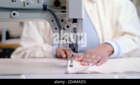 Schwarze Frau Schneiderhands mit einer Nähmaschine, Stoffkleidung industriellen Hintergrund Konzept mit Kopieplatz. Stockfoto