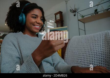 Glückliche Frau macht einen Online-Kauf mit Kreditkarte auf Das Sofa zu Hause Stockfoto