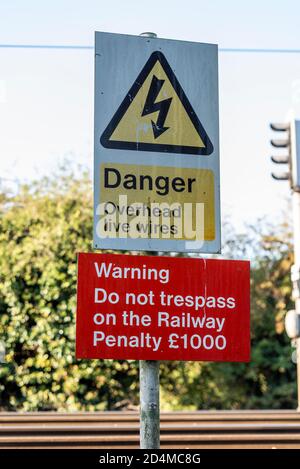 Gefahr, Oberleitungen. Warnung. Gehen Sie nicht in die Bahn. Strafgebühr £1000. Schilder auf dem öffentlichen Fußweg der Eisenbahnfußgängerzone in Rochford Essex Stockfoto