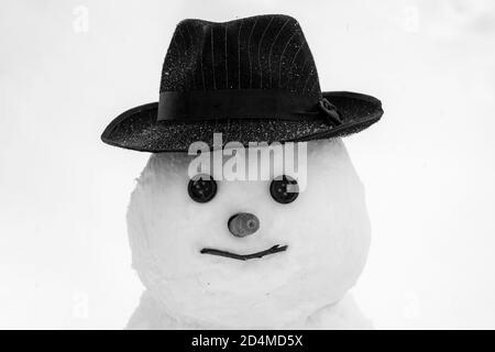 Lustige Schneemann in stilvollen Hut und Schal auf schneebedeckten Feld. Konzept für das neue Jahr. Netter kleiner Schneemann im Freien. Weihnachten Schneemann auf weißem Schnee Hintergrund Stockfoto