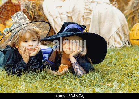 Kinder Schwester und Bruder mit Kürbis gekleidet wie Skelett und Hexe für Halloween-Party. Happy Halloween Kinder Mädchen und Junge sitzen auf Heu oder Stockfoto