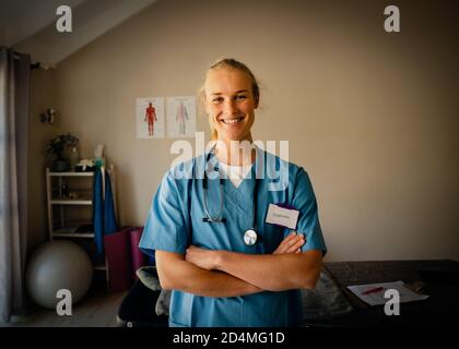 Porträt der jungen kaukasischen Ärztin in Scrubs, glücklich mit Ergebnis Stockfoto