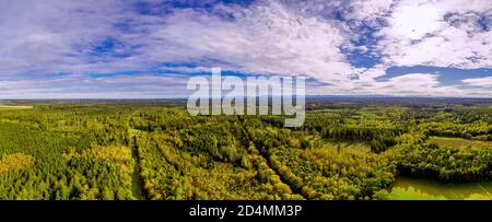 Weitwinkel-Drohnenpanorama von schönen Herbstlaub im Wald vor den bayerischen alpen unter dem blauen Himmel. Stockfoto