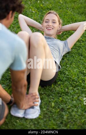 Mann hilft Frau mit Bauch Crunch Stockfoto