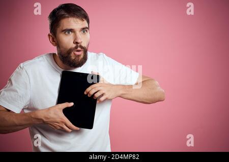 Mann wirbt eine Tablette auf einem rosa Hintergrund Codes Raum Beschnittene Ansicht der Emotionen weißes T-Shirt Modell neue Technologien Stockfoto