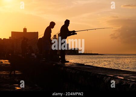 Schöner Sonnenuntergang in Havanna mit der Silhouette der Gruppe Fischer an der Malecon-Ufermauer Stockfoto