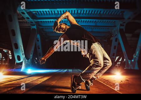 Junge coole Mann brechen Tänzer auf städtischen Brücke mit kühlen und warmen Licht Hintergrund. Tätowierung am Körper. Stockfoto