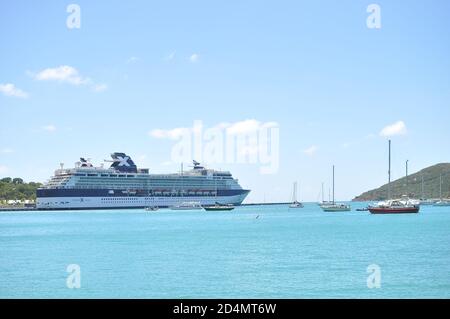 Celebrity Summit Cruiser in Red Hook Bay mit kleinen Booten im Wasser und blauen Himmel mit Wolken verankert. Stockfoto