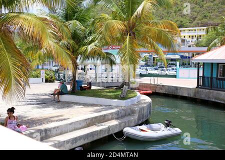 Otinerary in Philipsburg St. Maarten.Touristen ruhen und genießen den Schatten unter schönen Palmen neben dem Kanal mit einem Boot verankert. Stockfoto