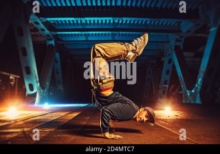 Junge coole Mann brechen Tänzer auf den Händen auf dem Kopf stehen. Urban Brücke mit kühlen und warmen Licht Hintergrund. Stockfoto