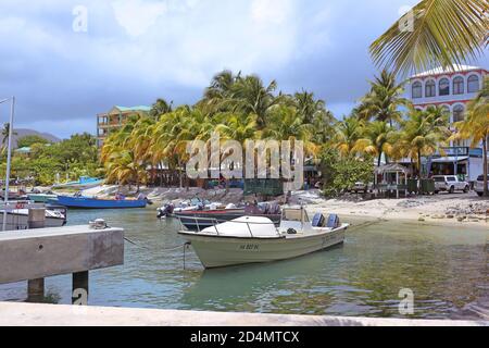 Boote ankerten am Ufer neben dem Yachthafen mit großen Palmen und Restaurants im Hintergrund. St. Martin, Karibik. Stockfoto