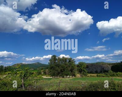 Himmel, Wolken, grüne Hügel und Bäume in Bulgarien. Wolkiger blauer Himmel. Stockfoto