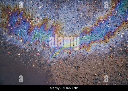 Ölfleck auf dem Asphalt, farbige Flecken von Benzin auf der Asphaltstraße, die in eine Pfütze fließen Stockfoto