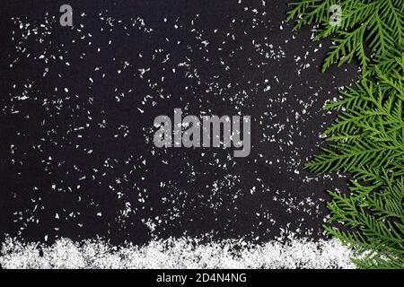 Grüner Christmasbaum aus Nadelbaumzweigen und Schneeflocken auf dunklem Grund. Minimaler Kompositionshintergrund. Neujahr und Weihnachten Kontra Stockfoto