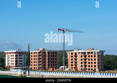 Turmdrehkran auf einer Baustelle. Bau von Hochhäusern mit mehreren Wohnungen. Neues Gebäude. Stockfoto