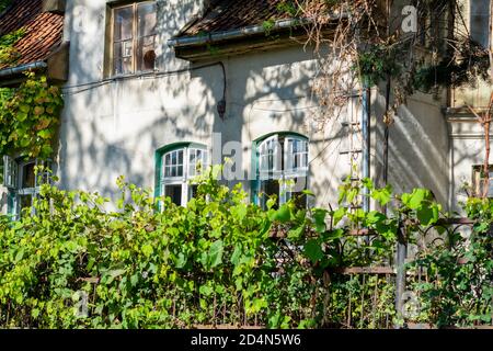 Fassade eines alten Hauses mit Holzfenstern und Fliesen. Haus aus dem 19. Jahrhundert ohne Restaurierung. Stockfoto