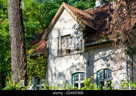 Haus aus dem 19. Jahrhundert mit gefliestem Dachfenster. Fassade Details, schöne alte Hütte im Wald. Stockfoto