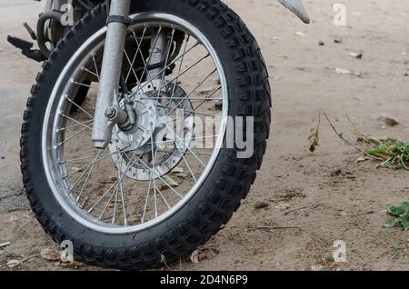 Vorderrad eines Mountainbikes, das auf dem Boden steht. Reisen Sie mit dem Motorrad im Gelände und in der Wildnis. Sport und aktiver Lebensstil. Stockfoto