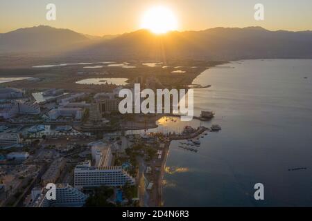 Sonnenaufgang über Eilat und dem Roten Meer, mit Hotels am Wasser und Edom Bergrücken am Horizont, Luftblick. Stockfoto