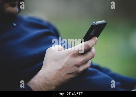 Details mit den Händen eines Mannes, der ein Mobiltelefon benutzt. Stockfoto