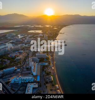 Sonnenaufgang über Eilat und dem Roten Meer, mit Hotels am Wasser und Edom Bergrücken am Horizont, Luftblick. Stockfoto