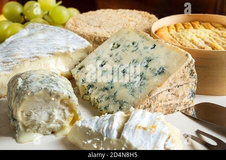 Französischer Käse - Camembert, roquefort, Brie, Ziegenkäse und Epoisse mit Trauben aus der Nähe Stockfoto