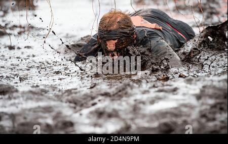 Schlammläufer. Krabbeln, unter einem Stacheldraht Hindernisse während extremer Hindernis Rennen passieren. Extremes Sportkonzept Stockfoto