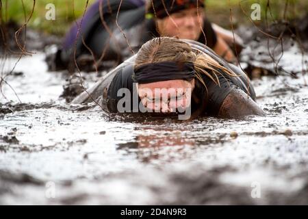 Schlammläufer. Krabbeln, unter einem Stacheldraht Hindernisse während extremer Hindernis Rennen passieren. Extremes Sportkonzept Stockfoto