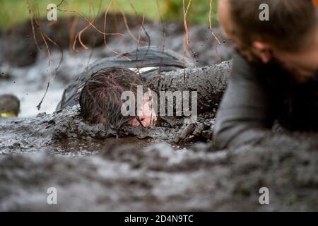 Schlammläufer. Krabbeln, unter einem Stacheldraht Hindernisse während extremer Hindernis Rennen passieren. Extremes Sportkonzept Stockfoto