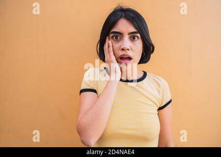 Porträt von jungen schönen Frau mit schockiertem Ausdruck isoliert vor gelbem Hintergrund. Stockfoto