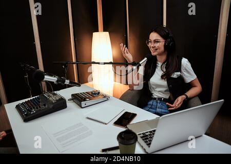 Portait von attraktiven jungen weiblichen Radio-Host, die fröhlich beim Sprechen im Mikrofon, Moderation einer Live-Show Stockfoto