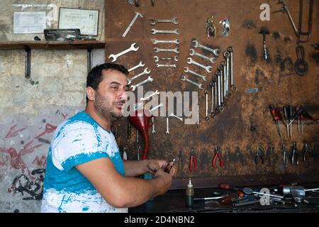 Hatay/Türkei - September 13 2020: Arbeiter Mann und verschwommene Wand mit verschiedenen Werkzeugen. Stockfoto