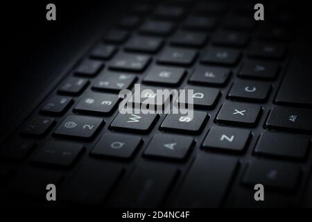 Nahaufnahme der schwarzen Laptop QWERTY Tastatur mit Licht fällt auf Tasten. Stockfoto