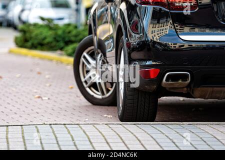 Nahaufnahme eines schwarzen, glänzenden suv-Autos, das auf dem Bürgersteig auf einem Parkplatz in der Nähe des Büros geparkt ist Stockfoto