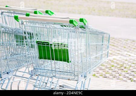 Mehrere leere grüne Einkaufswagen außerhalb des Lebensmittelladens, niemand. Viele einfache Shop Trolleys im Freien auf der super sam, 24-Stunden-Geschäft Stockfoto