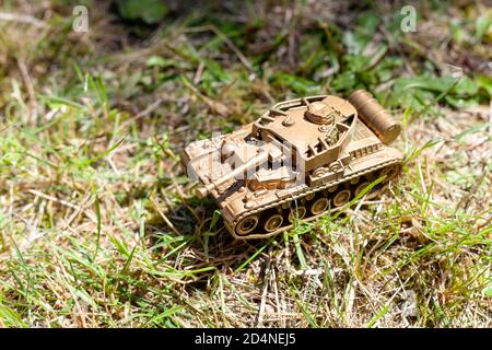 Gold Tank Kunststoff Spielzeug auf dem Boden. Golden Tank, Militärfahrzeug bewegt sich durch das Gras einfache billige Spielzeug für Kinder, Krieg, Kriegsgebiet Stockfoto