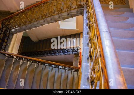 Eine alte Treppe mit goldenem Metallgeländer in leerem Gebäude. Stockfoto