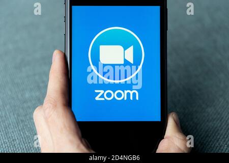 Telefon mit einer Hand, die die Zoom Cloud Meetings-App zeigt. Arbeiten und Meetings von zu Hause aus mit einem Smartphone abhalten. Stockfoto