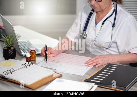 Kardiologin, die in der medizinischen Praxis ein EKG-Diagramm untersucht Stockfoto