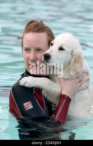 Cheltenham, Großbritannien. 10. Oktober 2020. Tracy Oliver umarmt ihren Welpen Brian, 16 Wochen alt. Hunde und ihre Besitzer haben die Möglichkeit, gemeinsam im Sandford Park Lido zu schwimmen, einem Freibad in Cheltenham, Gloucestershire, Großbritannien, am letzten Tag der Sommersaison, bevor der Pool für das Jahr geschlossen wird. Kredit: Thousand Word Media Ltd/Alamy Live Nachrichten Stockfoto