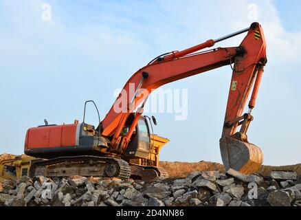 Schwerer Raupenbagger last Stein, mit alten Asphalt oder Beton Abfall in eine Mobile Backenbrecher Maschine. Die Zerkleinerung und Verarbeitung in Kies für Recycling Stockfoto