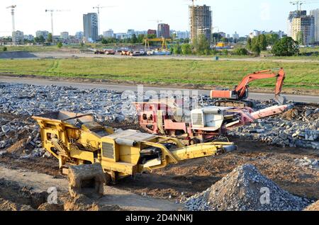 Schwerer Raupenbagger last Stein, mit alten Asphalt oder Beton Abfall in eine Mobile Backenbrecher Maschine. Die Zerkleinerung und Verarbeitung in Kies für Recycling Stockfoto