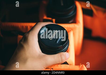 Fotograf nimmt 18-55mm Canon Objektiv aus seiner Kameratasche. Stockfoto