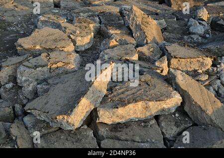 Zerbrochene Asphaltstücke auf einer Baustelle. Recycling und Wiederverwendung zerkleinerten Betonschutt, Asphalt, Baumaterial, Blöcke. Zerkleinert сoncrete Bac Stockfoto