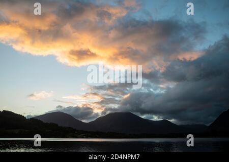 Atemberaubendes Landschaftsbild bei Sonnenaufgang mit Blick über Loweswater im See Bezirk in Richtung Low Fell und Grasmere mit bunten Himmel brechen Auf dem Berg Stockfoto