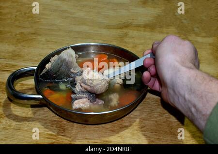 Fischsuppe in einer Metallplatte auf einem hölzernen Hintergrund. Traditioneller Essensangler oder Tourist Stockfoto