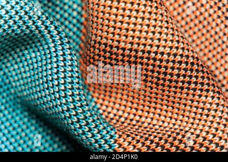 Ein Stapel mehrfarbiger synthetischer Strickstoffe mit verschiedenen Strukturen und Texturen. Ein Stapel von bunten Stoffen glatte Formen Hintergrund. Multicol Stockfoto