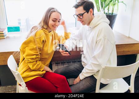 Der Typ und das Mädchen schauen auf das Smartphone und kommunizieren. Stockfoto