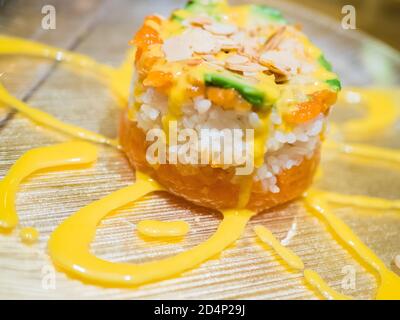 Typisch japanisches Gericht mit Sushi, Reis und Fisch, mit Sauce, Salat, Sushimi und Sesam. Japanischer Burger mit Reis, Lachs, Avocado, Mandeln und d Stockfoto