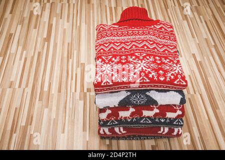 Stapel gefalteter gestrickt Weihnachten rollkragen pullover oder Pullis mit Nordic Ornament auf Holz- Hintergrund gefaltet Stockfoto